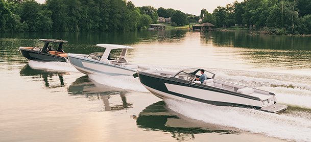 Three sleek Aviara models speed across a calm lake, creating white wakes.