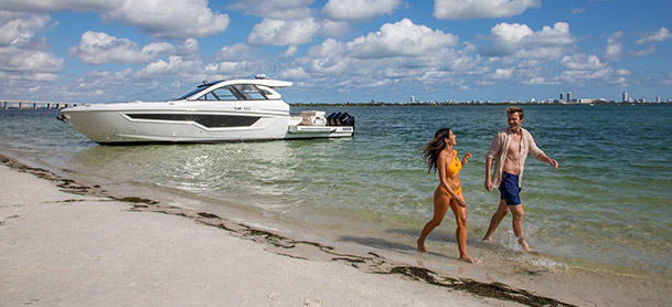 Couple on the beach with a Cruisers Yachts boat in the water