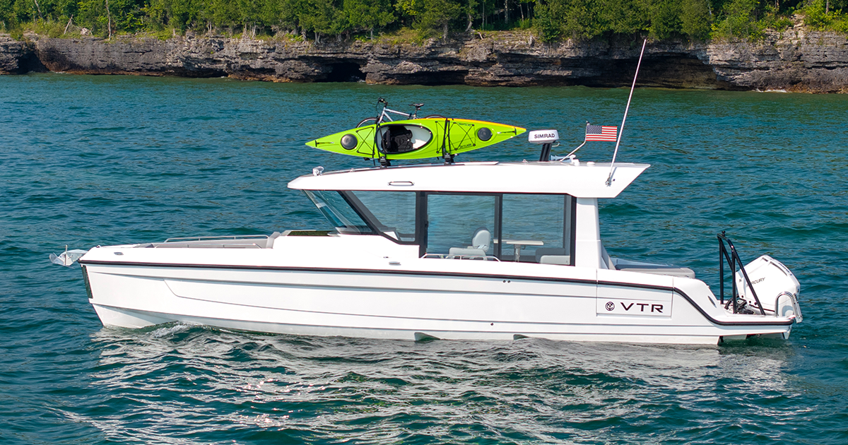 A 38 VTR EC cruises on blue waters, a bright green kayak secured on its roof.