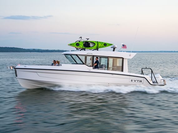 A 38 VTR EC carries a green kayak on top and flies an American flag, evoking adventure and freedom.