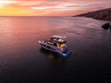 Cruisers Yachts 57 FLY sitting still at a dramatic sunset on the water. 