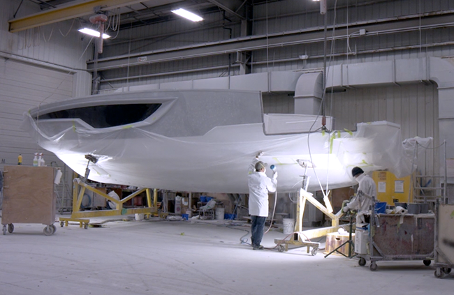 Craftsmen hand-finishing a boat hull at the Cruisers Yachts manufacturing facility